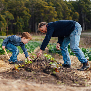 Man and child gardening together in a field with trees in the background wearing Blundstone Boots 630 Series